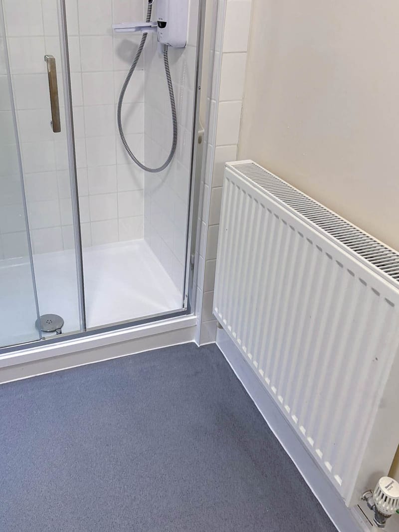The same bathroom, along the shower and radiator wall, after the works